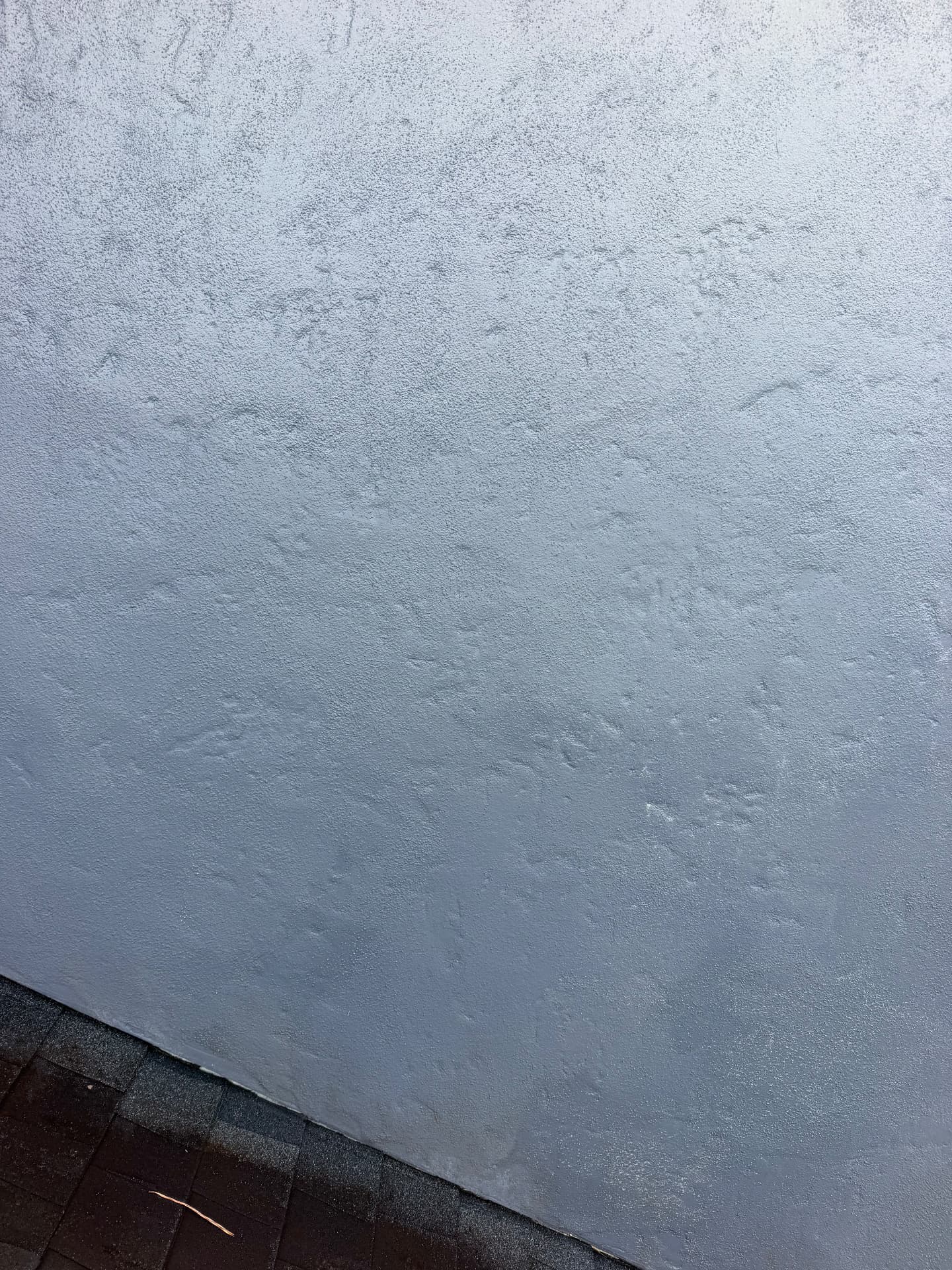 The same painted stucco wall and shingle roofline clean and even after low-pressure house soft washing