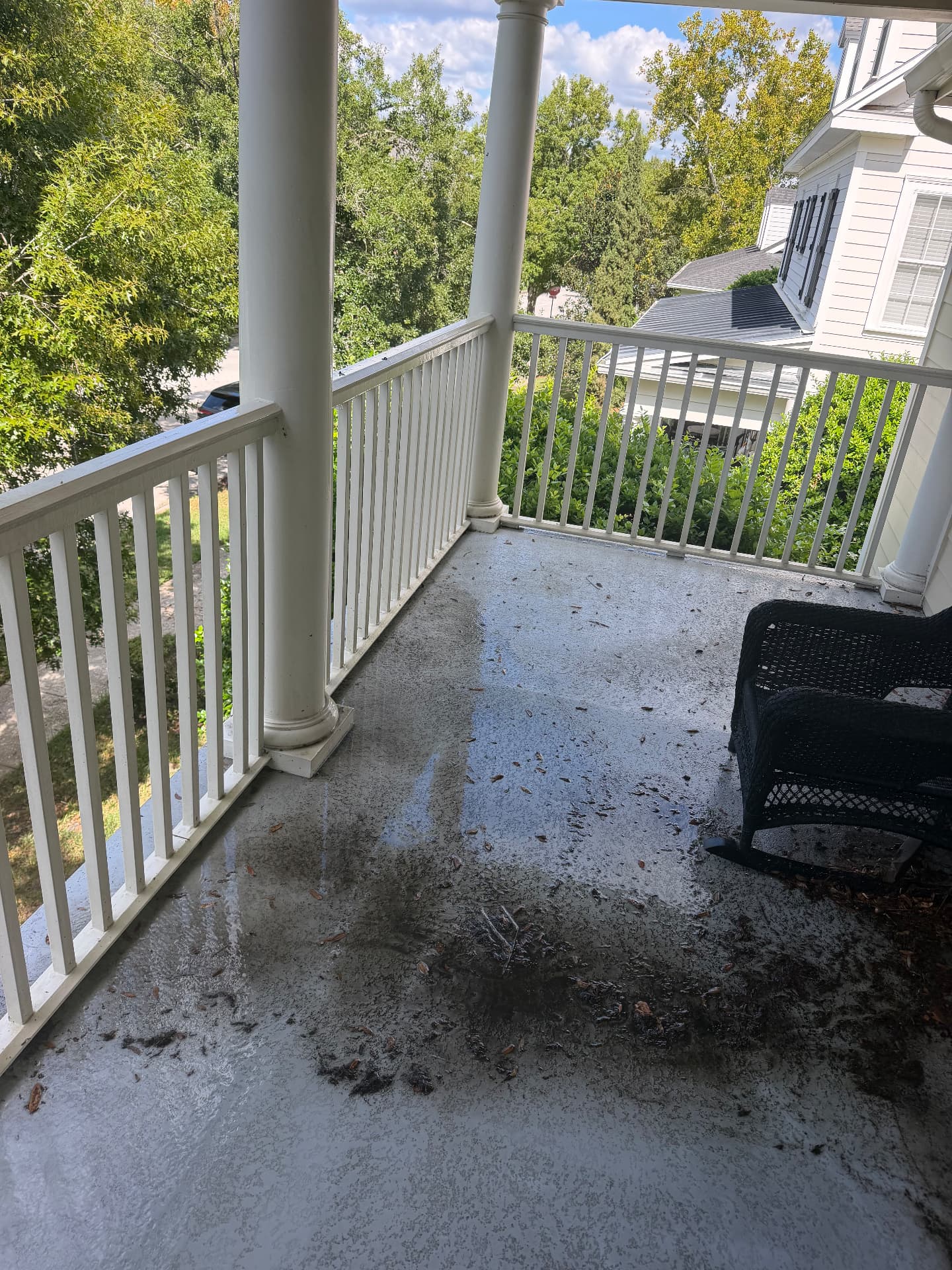 Second-story covered porch deck covered in wet leaves, dirt and organic sludge before pressure washing on a Central Florida home