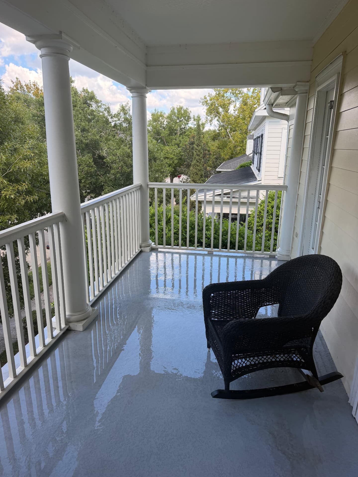 The same covered porch deck rinsed free of dirt and debris after pressure washing, clean coated floor reflecting the columns